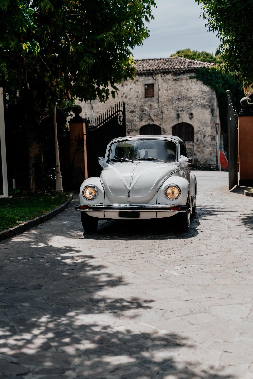Maggiolino Cabrio bianco davanti al cancello della villa