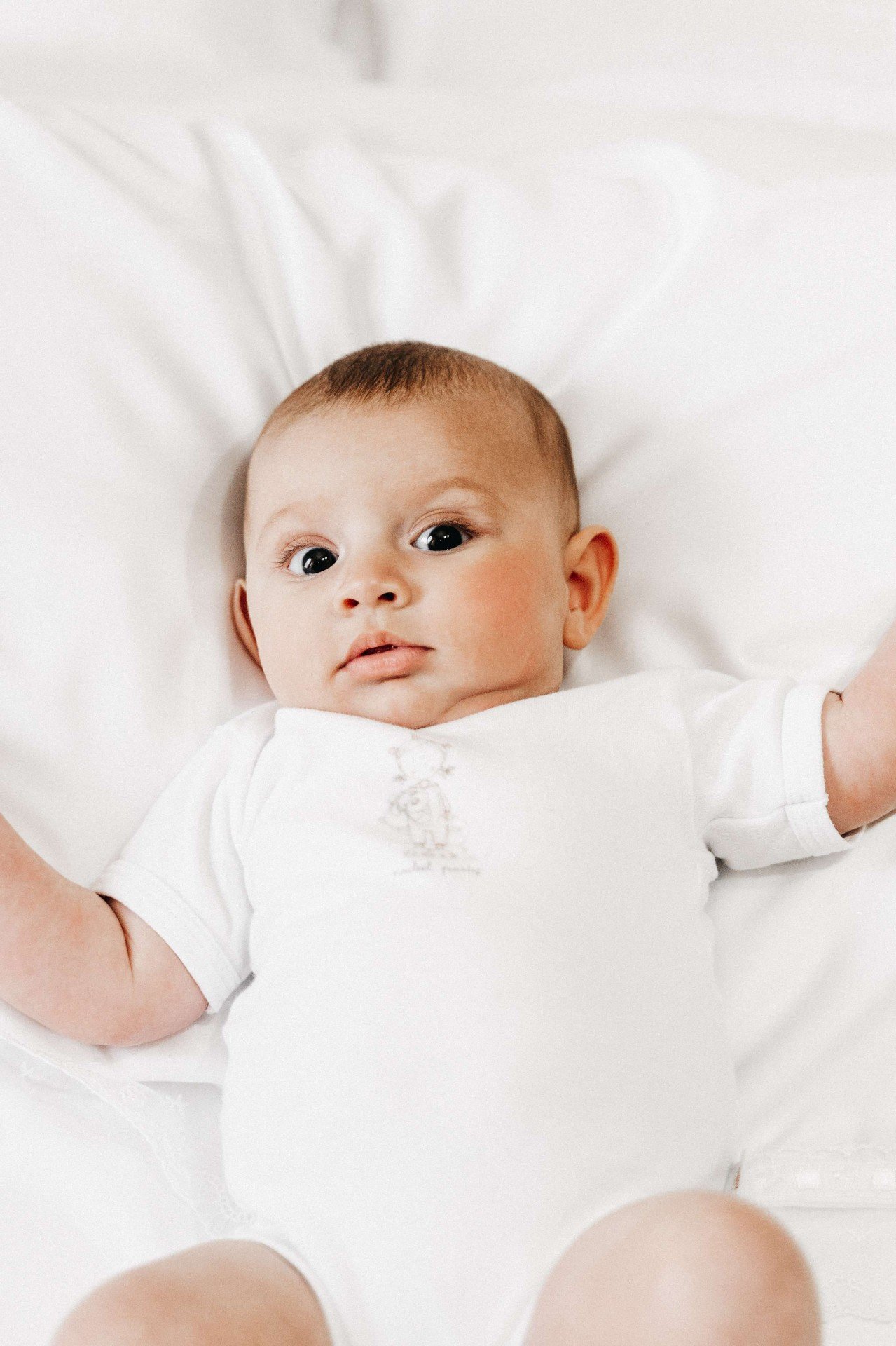 Neonata con body bianco, supina