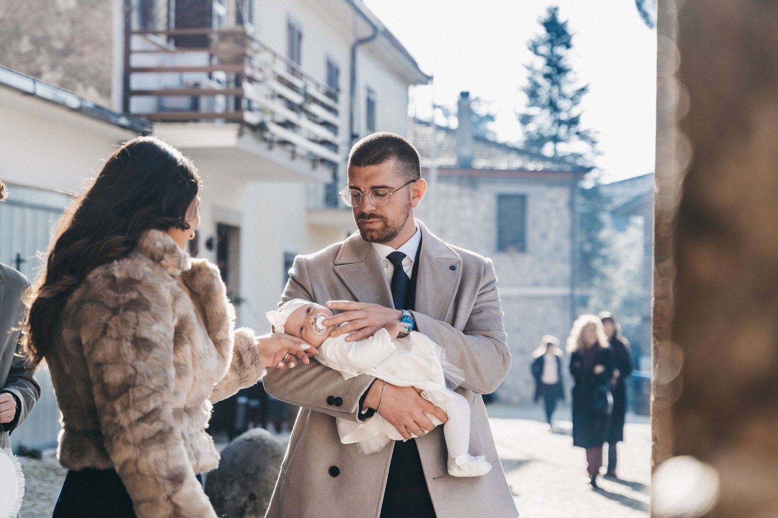 Papà con la neonata in braccio nella luce del sagrato